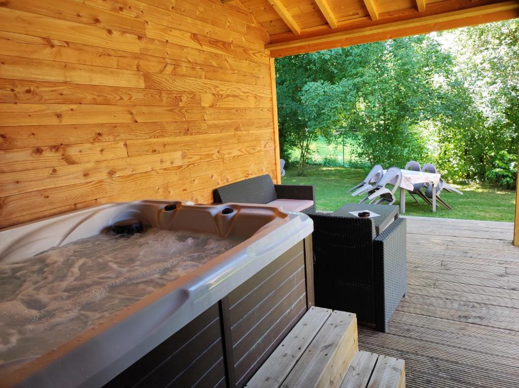 bañera de hidromasaje en una terraza de madera con mesa y sillas en Gîte avec SPA privé près zoo Beauval et châteaux, en Oisly