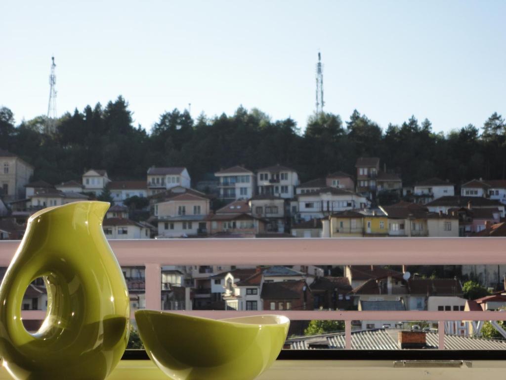 a green vase sitting on a window sill with a city at Accommodation Mell in Ohrid