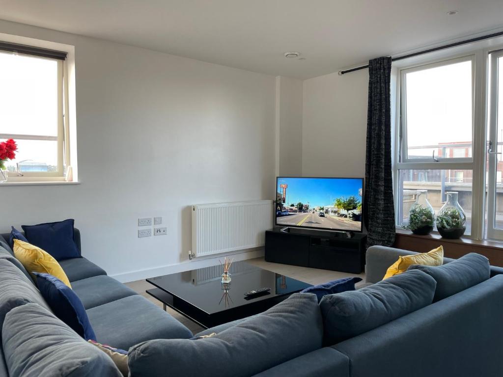 uma sala de estar com um sofá azul e uma televisão em Modern & Spacious Penthouse in North London em Londres