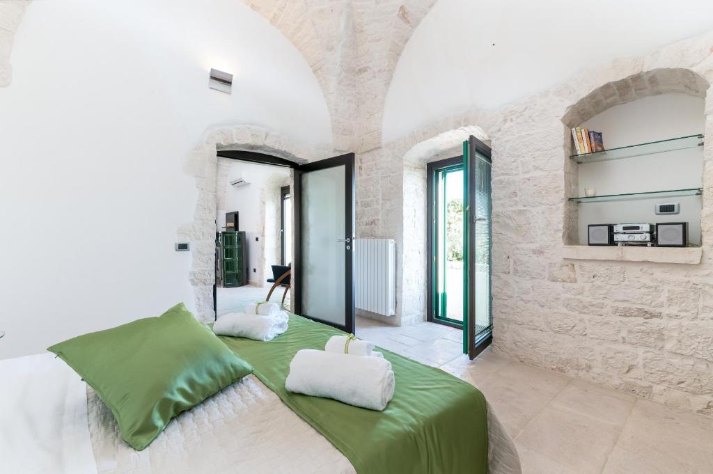 1 dormitorio con cama verde y pared de piedra en Suite Fronte Valle, en Cisternino