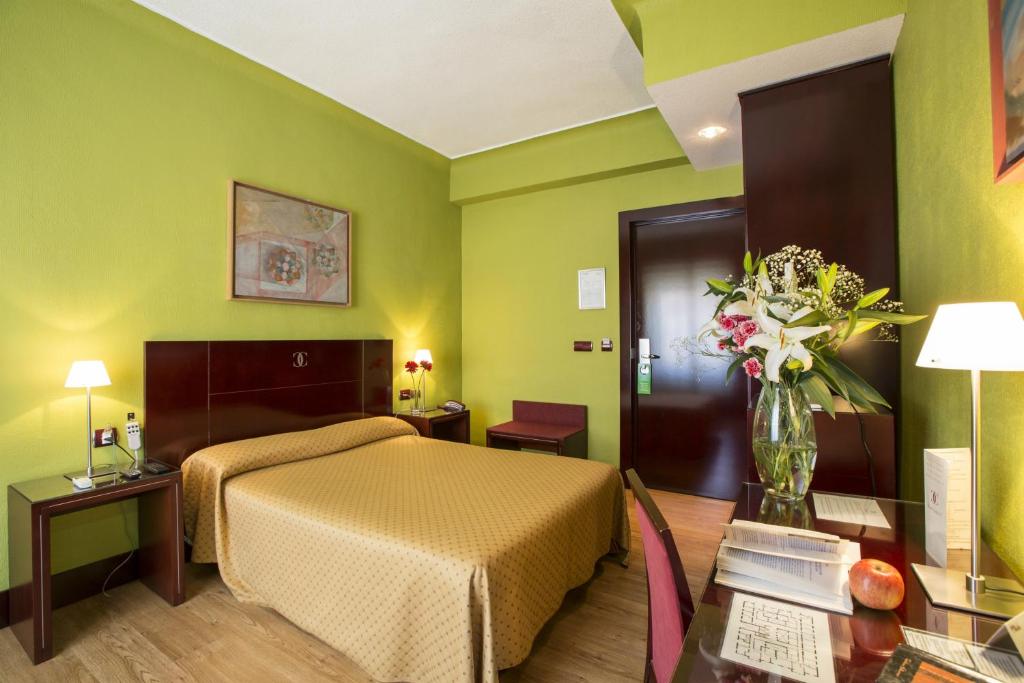 a hotel room with a bed and a vase of flowers at Hotel Carlos V in Granada