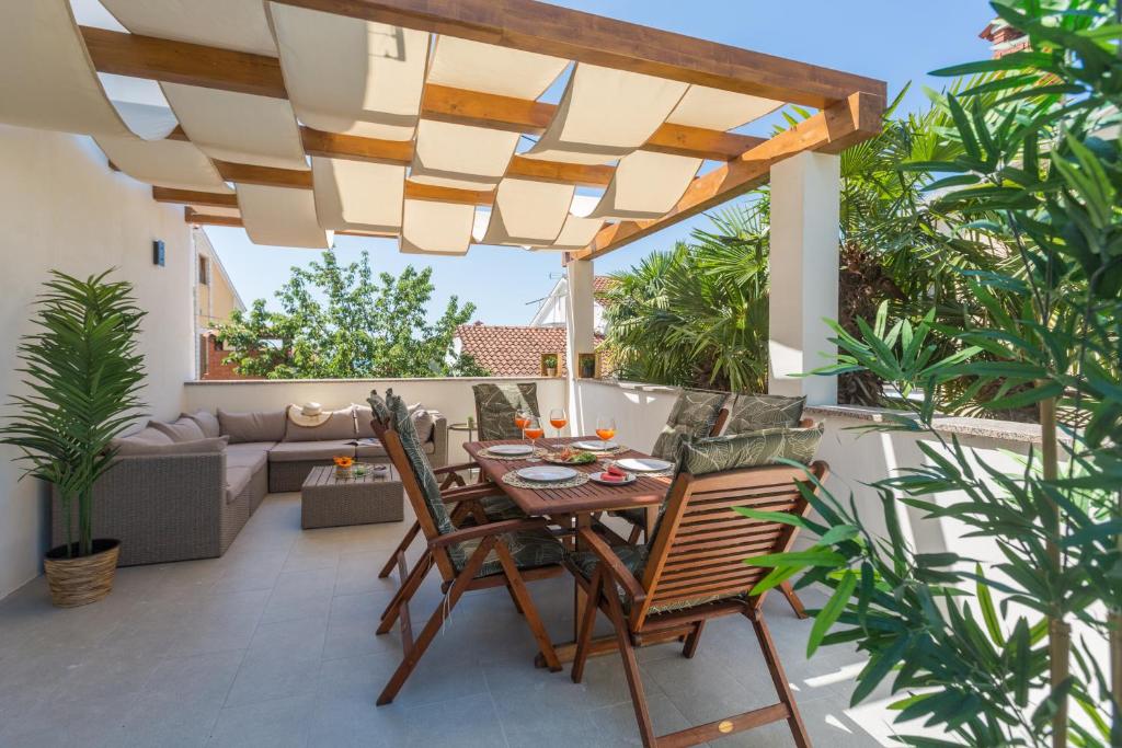 a patio with a wooden table and chairs under a pergola at Apartments Residence Radovan 1 in Poreč