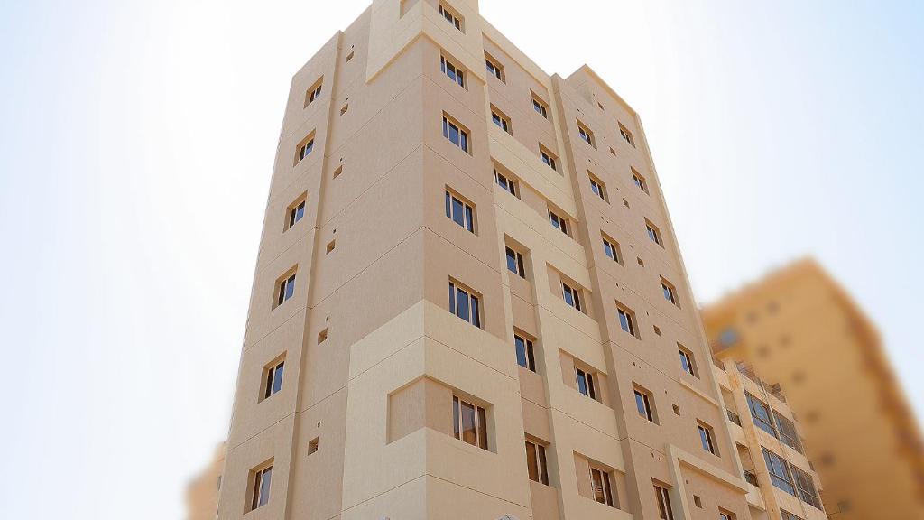 BHomed Furnished Apartments في الكويت: مبنى اسمر طويل مع نوافذ على الجانب منه