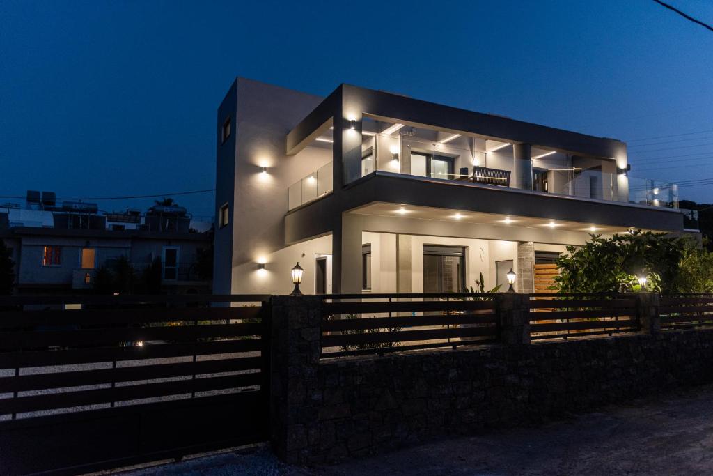 a house at night with a fence in front of it at Muse by the beach in Amoudara Lasithiou