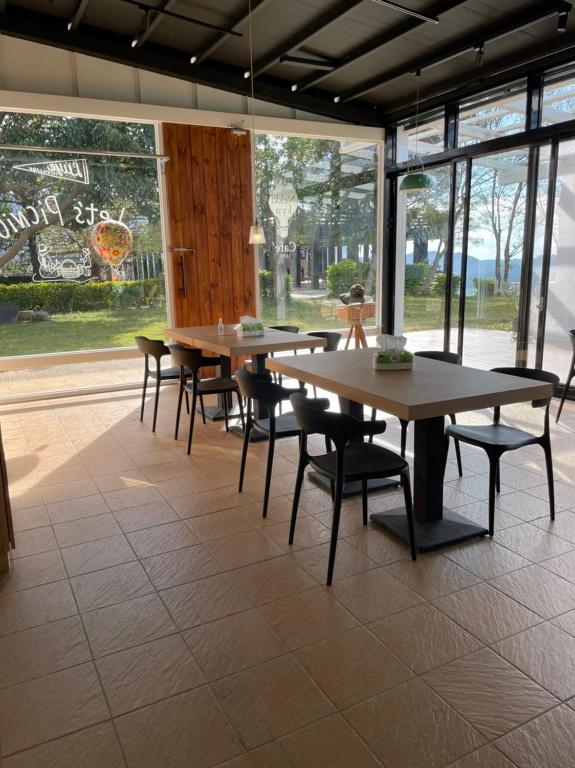 a row of tables and chairs in a room with windows at Lutai B&amp;B in Yung-an-ts&#39;un