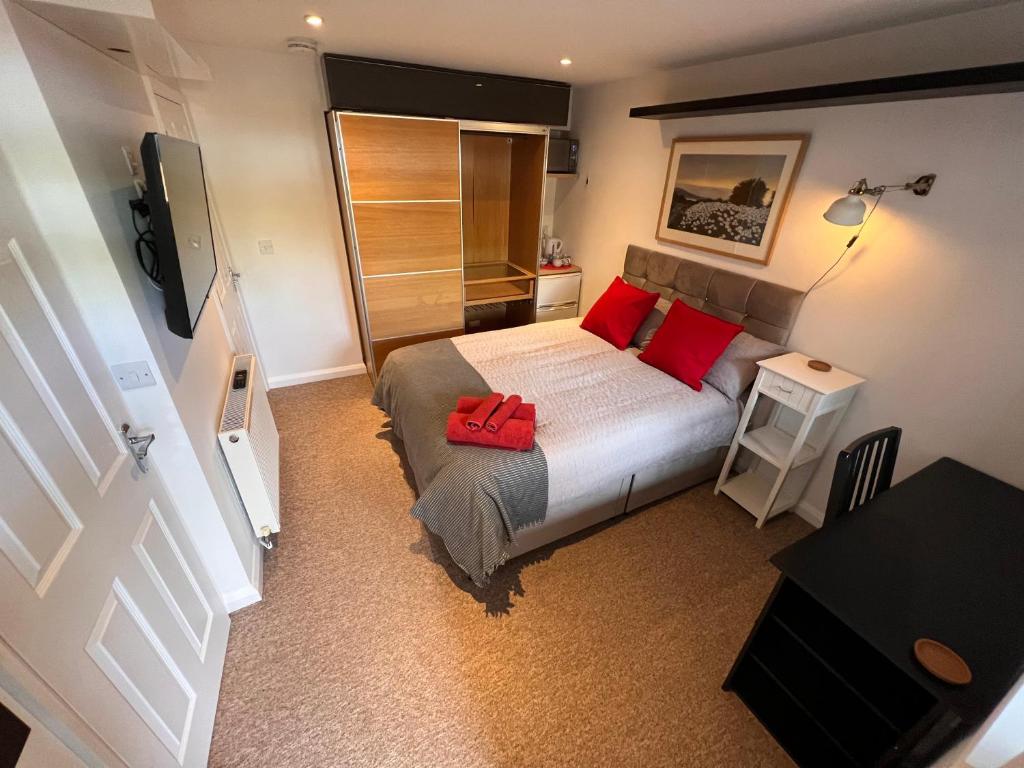 a small bedroom with a bed with red pillows at Central Room in Milton Keynes