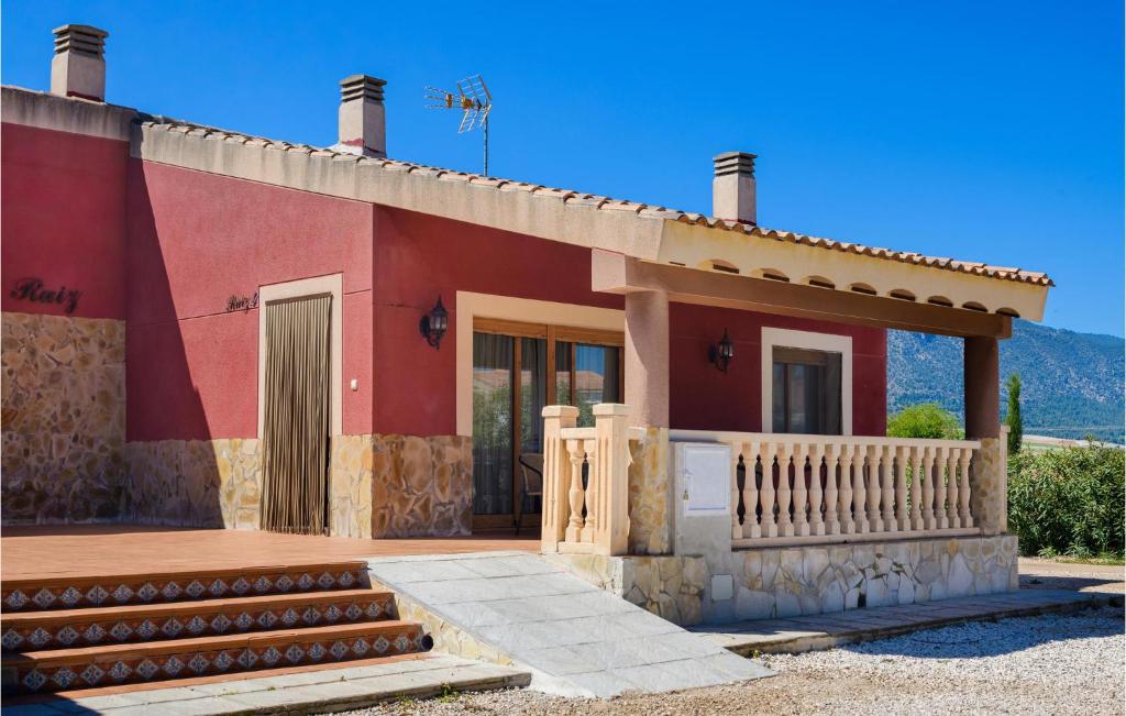 una pequeña casa roja con porche y puerta en Gorgeous Home In Caravaca De La Cruz With Outdoor Swimming Pool, en Inazares