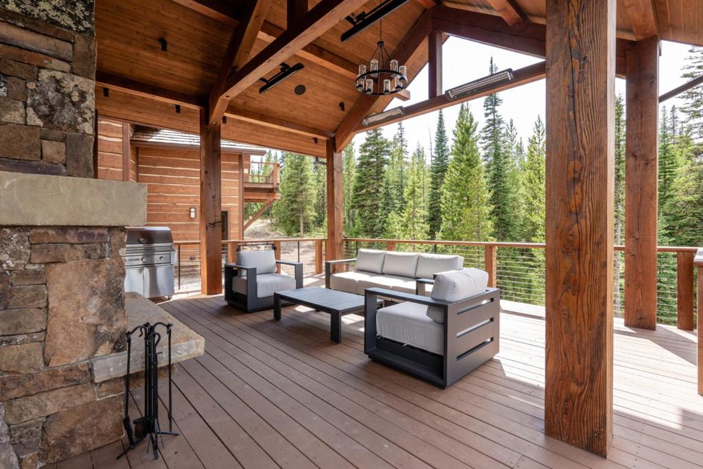 a wooden deck with a fireplace and furniture on it at Mountain Valley Estate in Big Sky