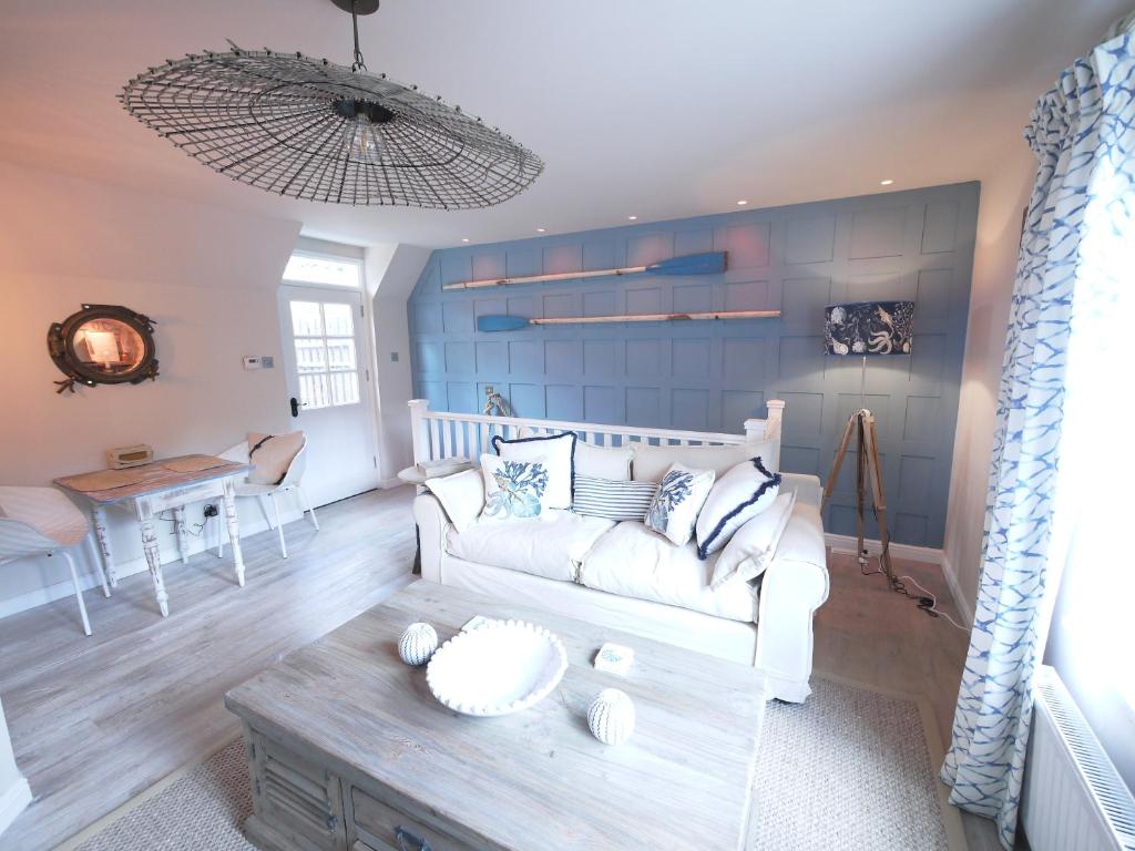 uma sala de estar com um sofá branco e uma mesa em The Wee Blue House, East Neuk em Lower Largo