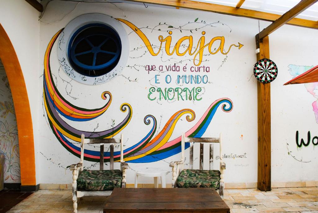 una pared con un mural con una mesa y sillas en World Hostel - Canasvieiras, en Florianópolis