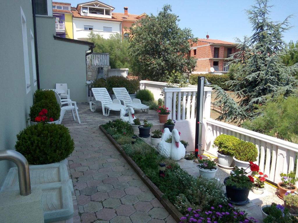 um pátio com cadeiras brancas e algumas plantas e flores em Petar em Pula