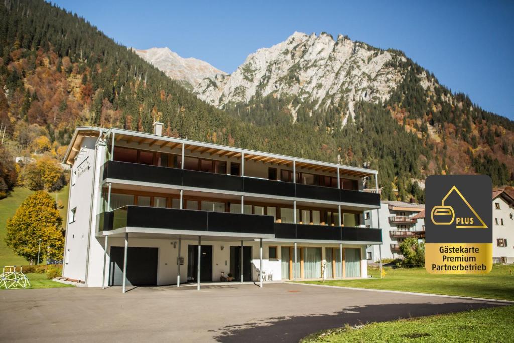 ein großes Gebäude mit einem Berg im Hintergrund in der Unterkunft Apart Sportiva in Klösterle am Arlberg