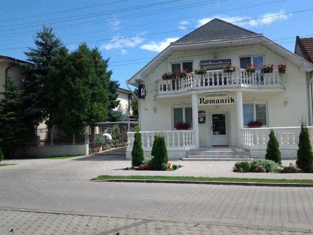 a white house with a balcony on a street at Penzion Romantik in Dolná Streda