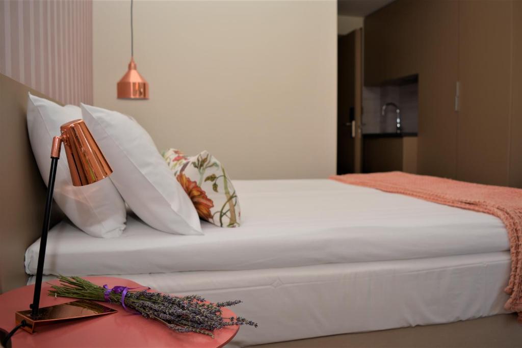 a bed with white pillows and a lamp on a table at The Archontariki in Ormos Panagias