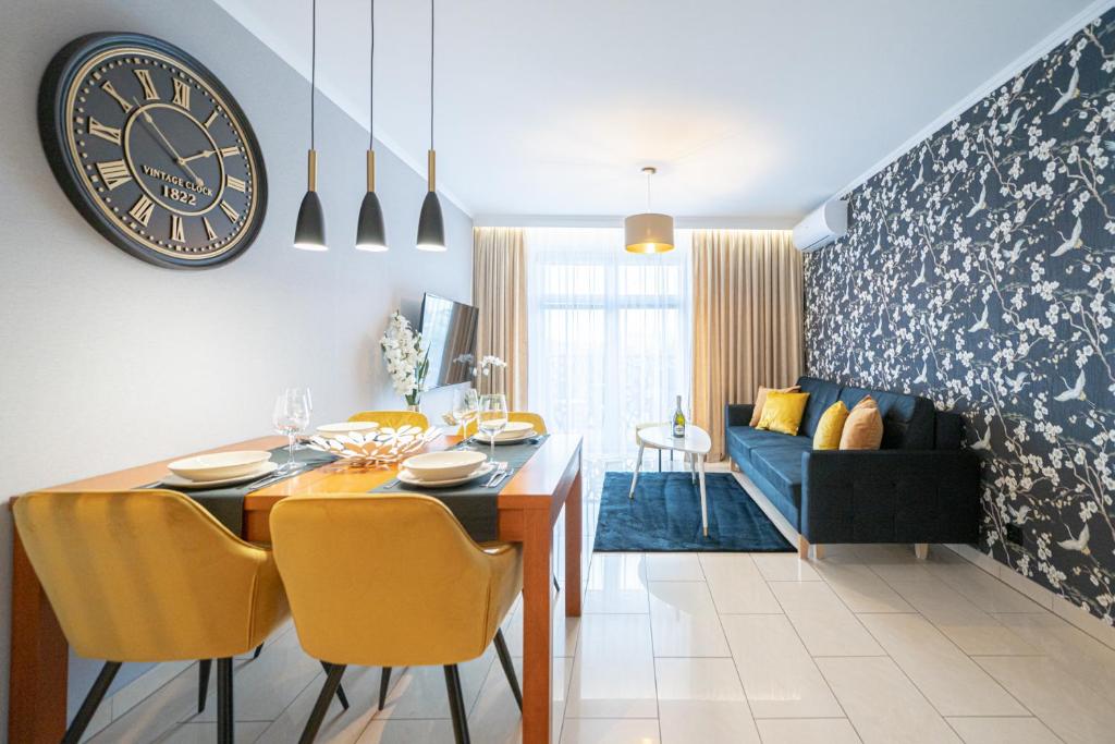 a dining room and living room with a clock on the wall at Apartament 55m2 - Darmowy Garaż - Klimatyzacja - Centrum - 24na7 in Wrocław