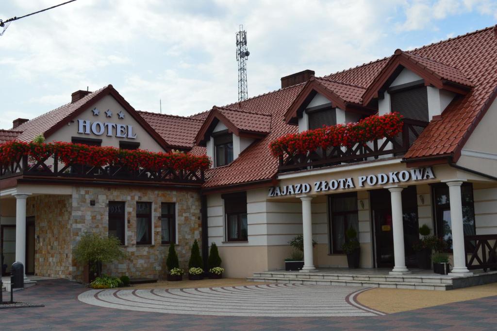 a hotel with red flowers in front of a building at Zajazd Złota Podkowa in Wrocki