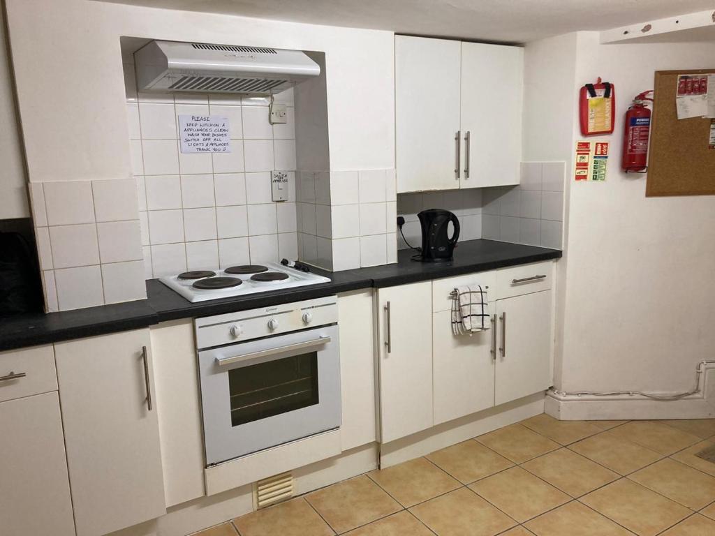 a kitchen with white cabinets and a stove top oven at Golden Triangle Budget Rooms in Norwich