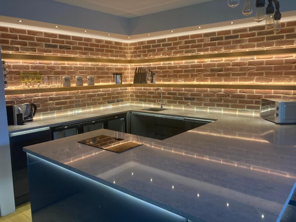 a kitchen with a sink and a brick wall at The Oaks Stable cottage in Haughley