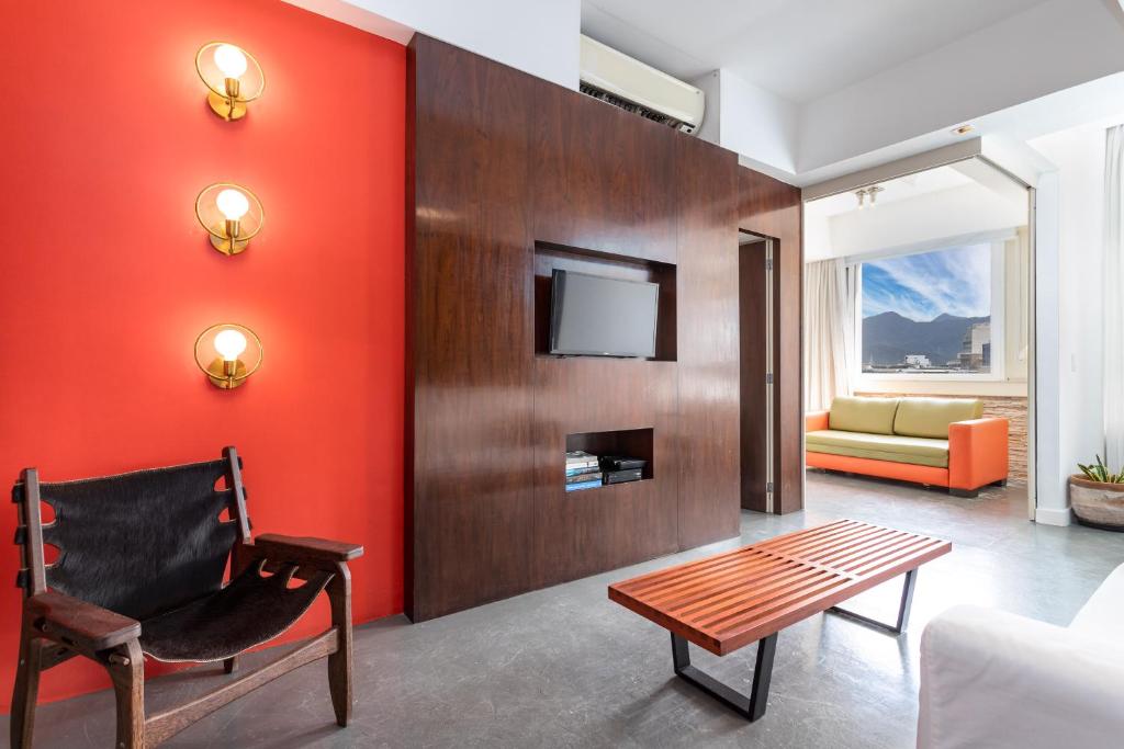 uma sala de estar com uma parede vermelha em Unhotel - Aluguel de Apartamento em Ipanema ao lado da praia no Rio de Janeiro