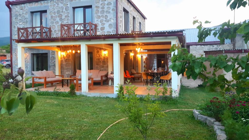 a house with a deck with a table and chairs at Old Tatev Guesthouse in Tatʼev