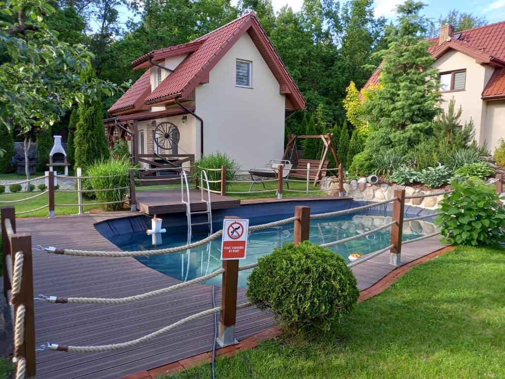 a wooden deck with a pool and a house at Domek całoroczny Wczasy jak Marzenie in Ruciane-Nida