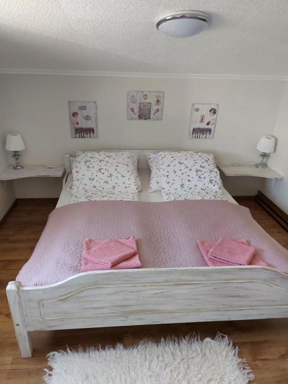um quarto com uma cama com lençóis cor-de-rosa e almofadas cor-de-rosa em Takler Home em Alsóörs