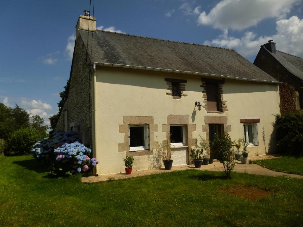 una casa blanca con flores delante en Belle maison familiale dans la campagne Bretonne, en La Croix-Helléan