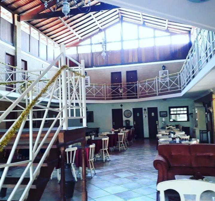 un restaurant avec un escalier, des tables et des chaises dans l'établissement Pousada Alto da Colina, à Conservatória
