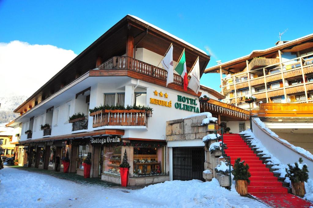 a hotel building with a red staircase in the snow at Hotel Olimpia in Cortina dʼAmpezzo