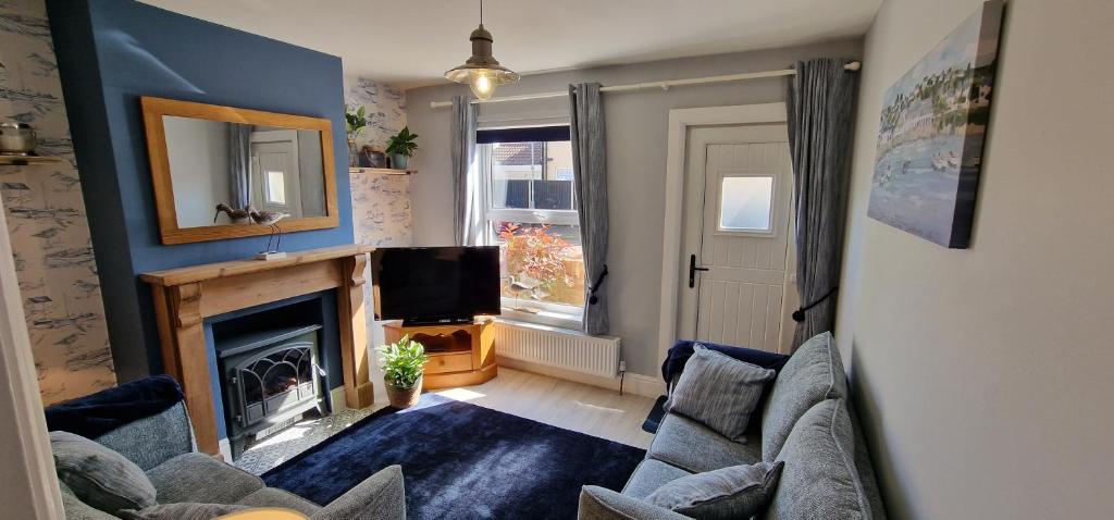 a living room with a fireplace and a tv at Curlew Cottage - Suffolk Coastal Escapes in Pakefield