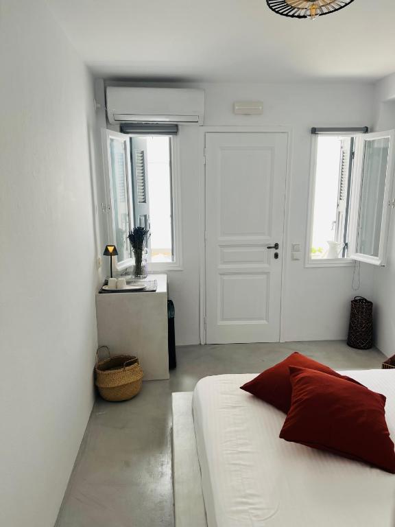 a white bedroom with a bed and a sink at Camara Homes in Andros