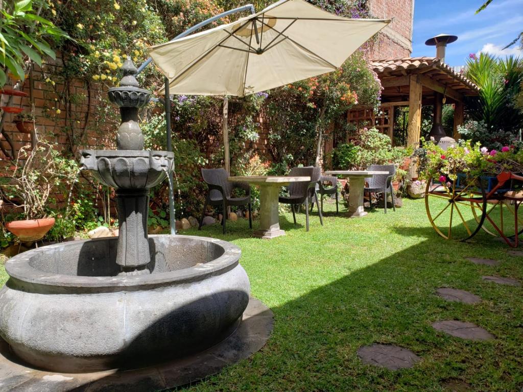 una fuente con una sombrilla en un jardín en Illas Inn, en Cusco