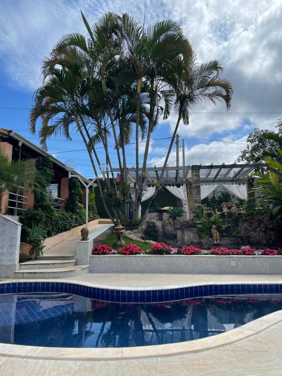 uma piscina com palmeiras e uma ponte em Pousada Villa São Francisco em Boituva