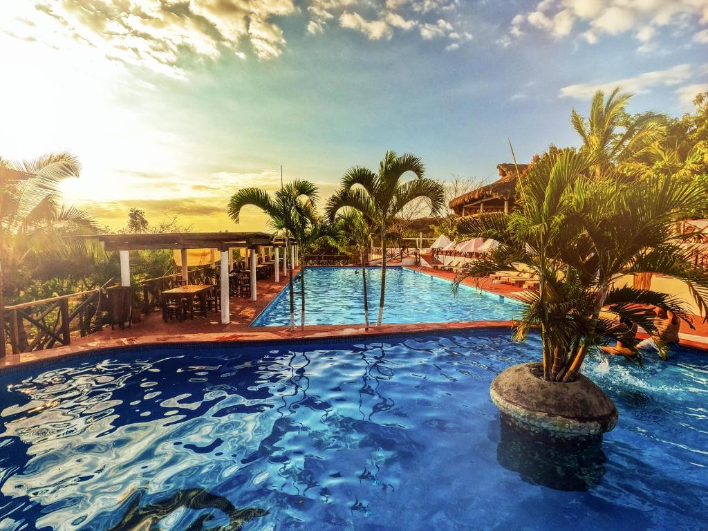 a resort pool with a palm tree in the middle at Casa Paraiso Hotel Boutique in Puerto Escondido