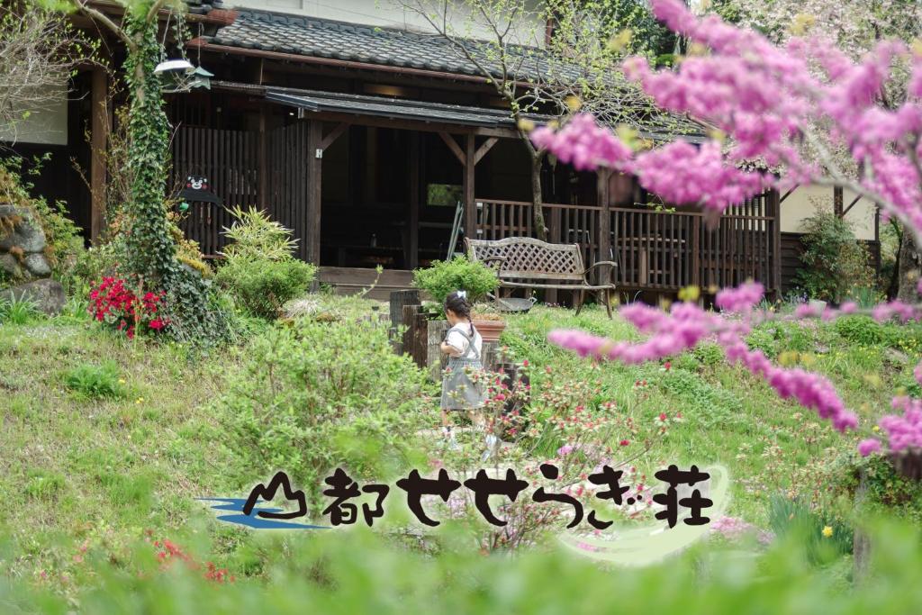 une femme debout dans un jardin devant une maison dans l'établissement Yamato Seseragi-so - Vacation STAY 67930v, à Kaneuchi