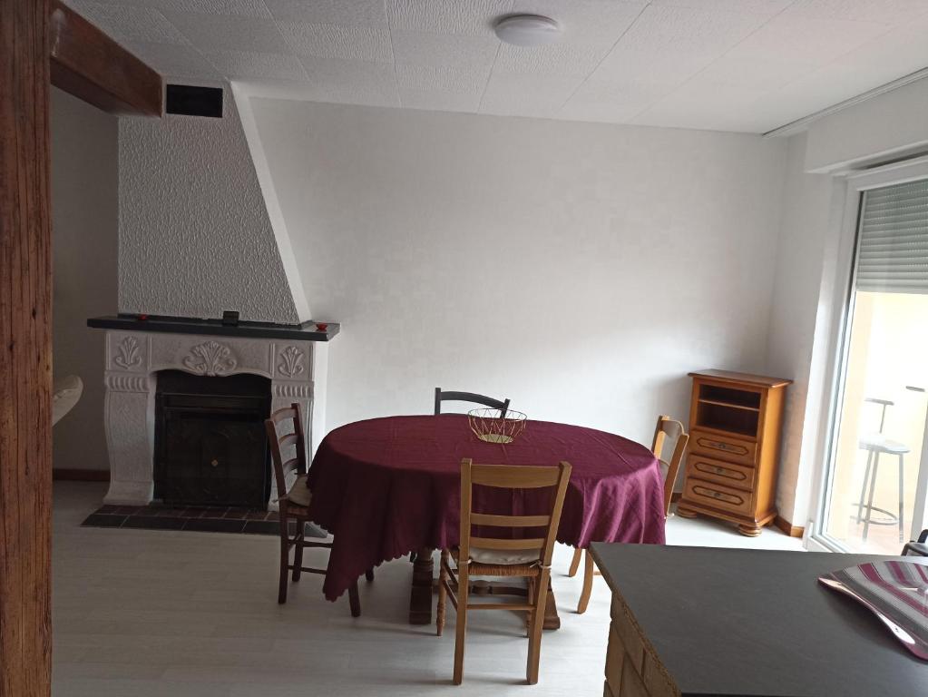 ein Esszimmer mit einem Tisch und einem Kamin in der Unterkunft appartement avec balcon in Hargarten-aux-Mines