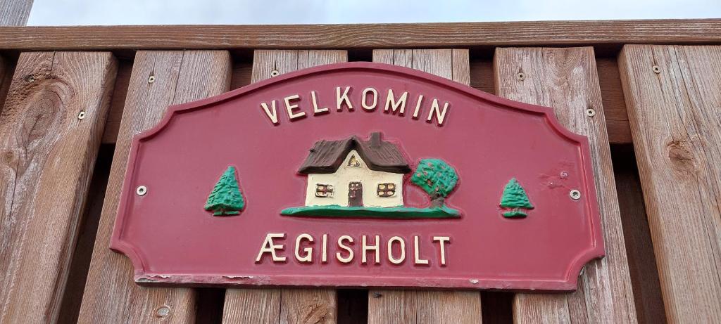 a red sign on a wooden fence with a house at Ægisholt privete house with hot tub in Patreksfjörður