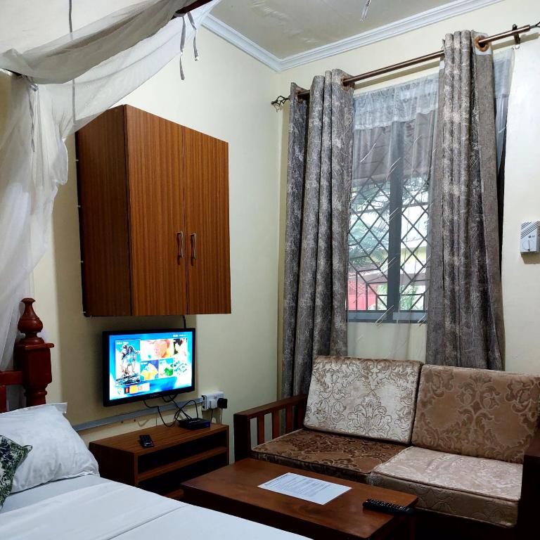 Amarossi Hippo-Studio Terrace Apartment, Mtwapa في متوابا: غرفة نوم بسرير واريكة وتلفزيون