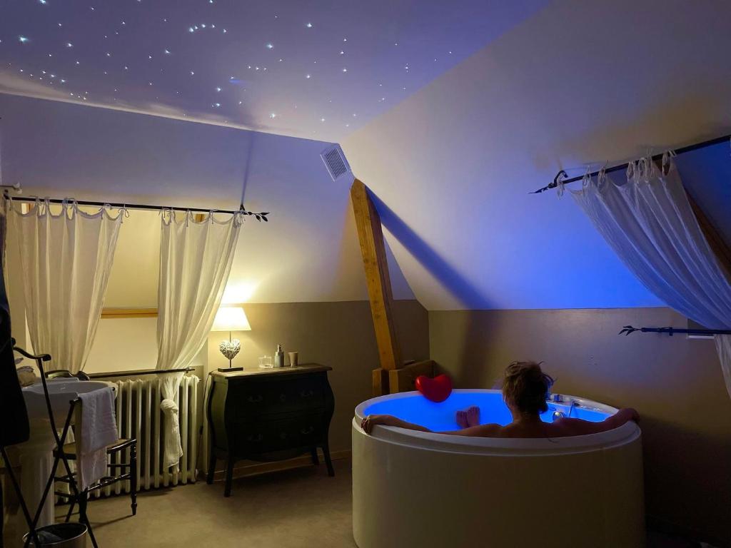 a person in a tub in a room with a star ceiling at Maison d'hôtes & SPA La Vallée Des Rêves in Nods