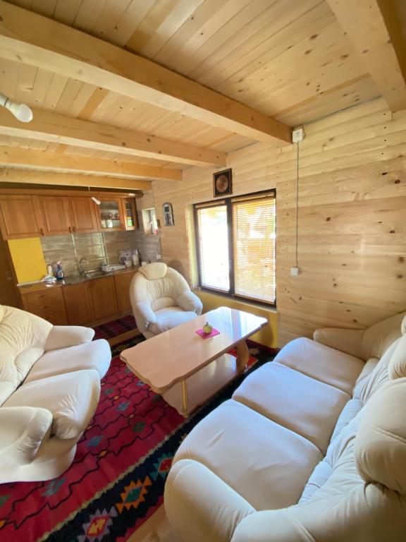 a living room with white couches and a table at Zlatna koliba Namir Zuka in Fojnica