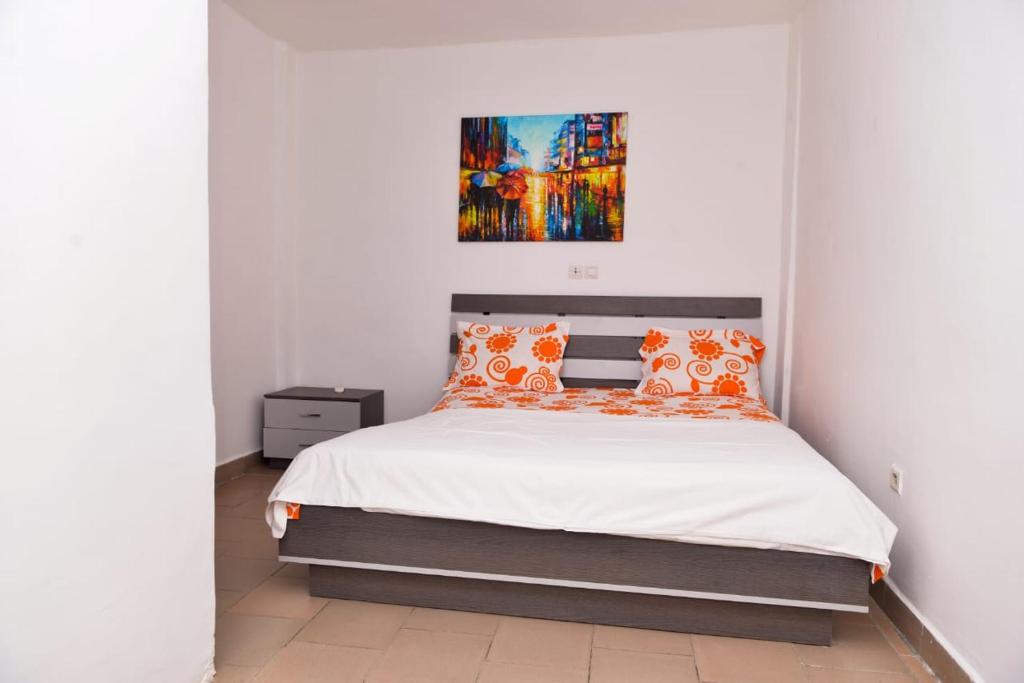 een slaapkamer met een bed met oranje kussens bij Studio lumineux in Douala