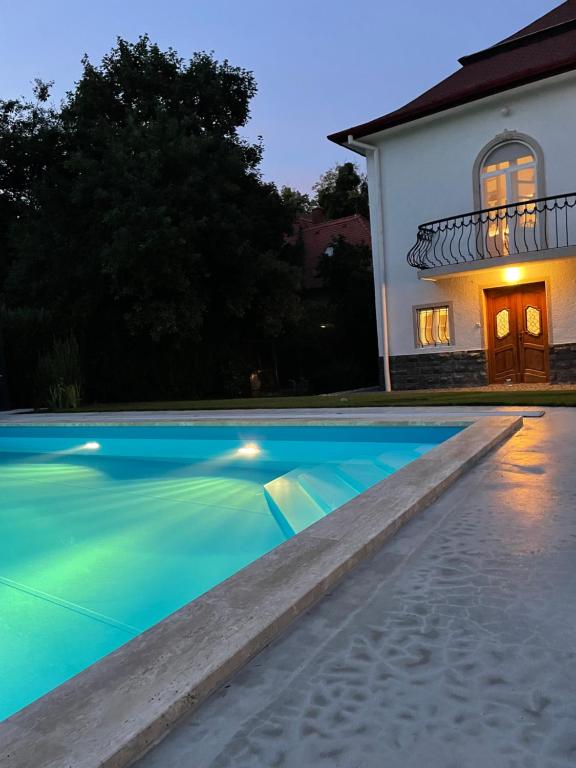 a swimming pool in front of a house at night at Vértessy ház in Keszthely