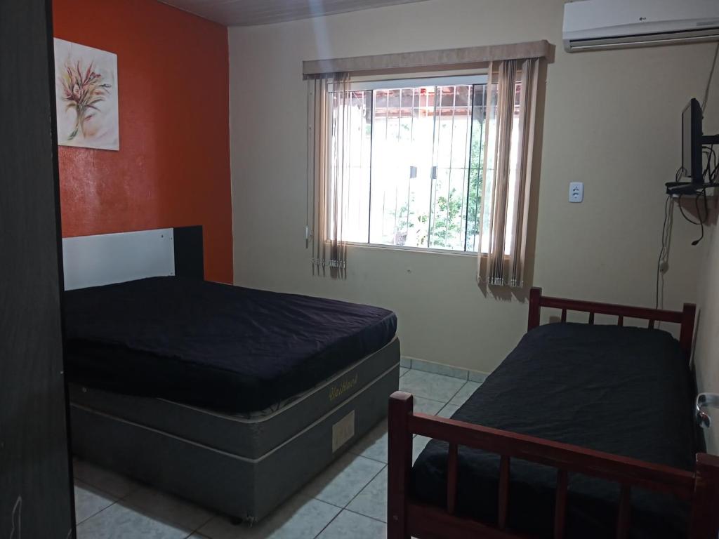 1 dormitorio con 2 camas y ventana en Casa de Praia Armacao de Itapocoroi 261 - Próximo ao Parque Beto Carrero World, en Penha