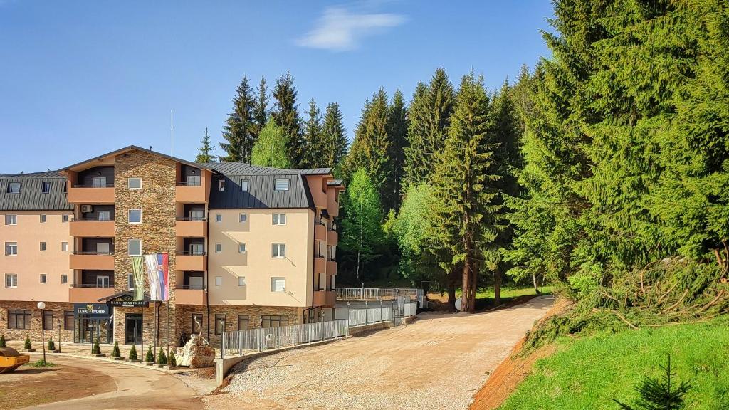um edifício de apartamentos numa estrada de terra ao lado de árvores em Ema apartman - Zlatar em Nova Varoš