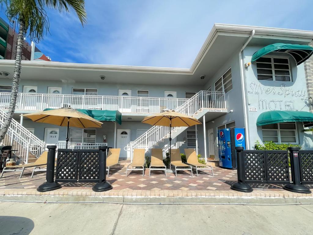 a building with chairs and umbrellas in front of it at Silver Spray Motel in Hollywood