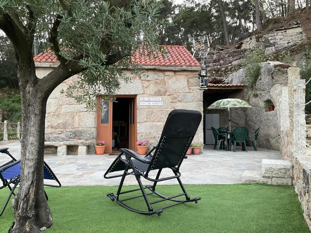 2 chaises longues assises à côté d'un arbre dans une cour dans l'établissement Val da fonte, à Ourense