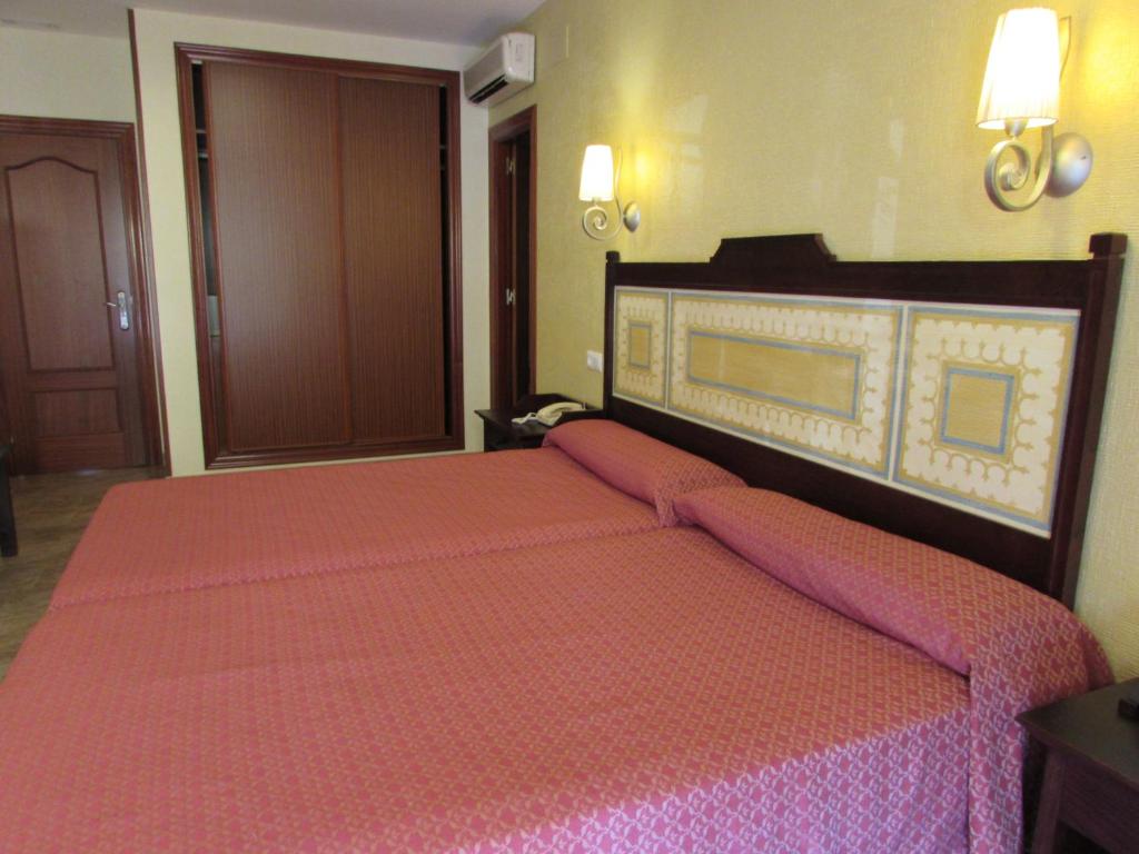 a bedroom with a large bed with pink sheets at PARAISO PLAYA Hotel in Isla Cristina