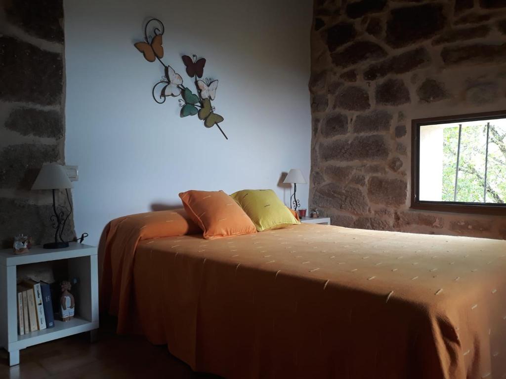 1 dormitorio con cama con sábanas de color naranja y ventana en Casa de pueblo en San Estevo Ribas de Sil, en Ourense