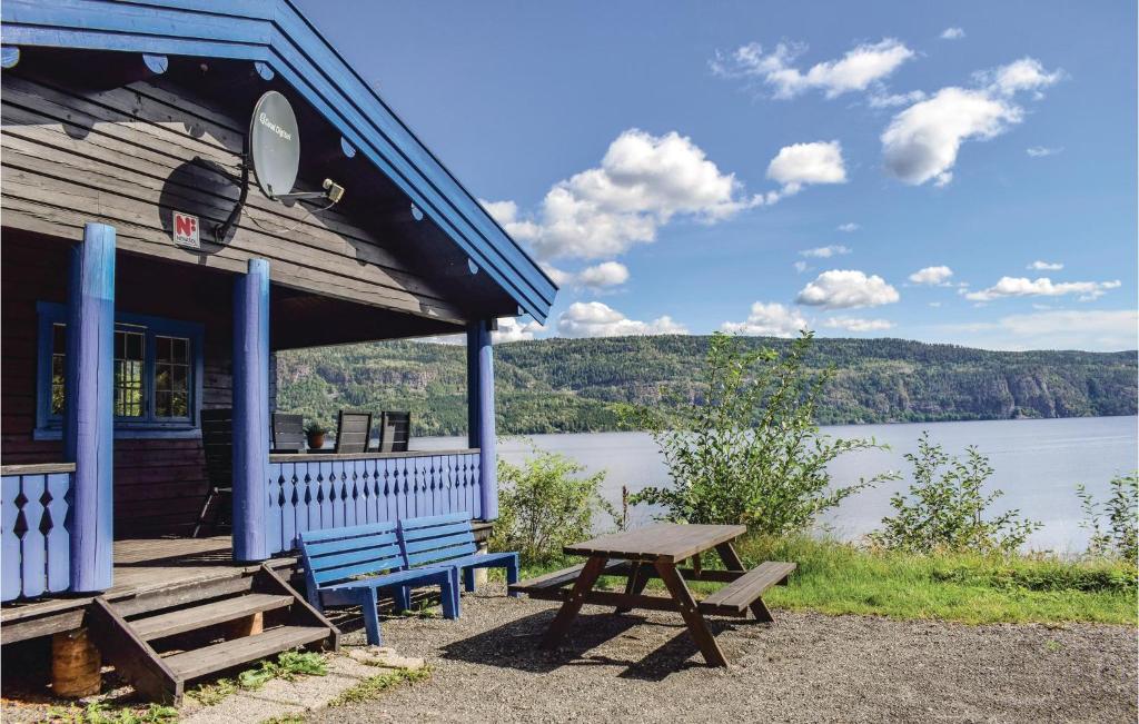 a blue building with a picnic table next to a lake at Solbakken in Vikersund