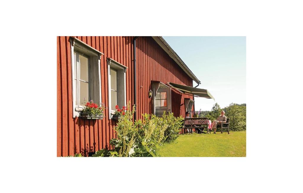 a red house with a person sitting on a bench next to it at Nice Home In Dals Lnged With 2 Bedrooms in Dals Långed